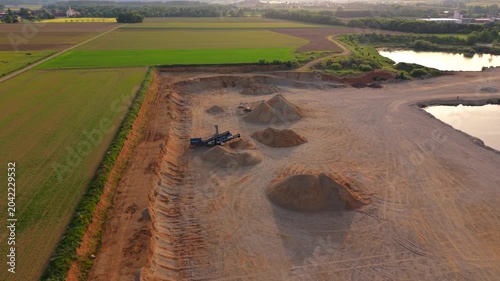 Aerial drone footage of construction material production showing aggregate stockpiles, extraction areas and processing facilities within a modern gravel quarry