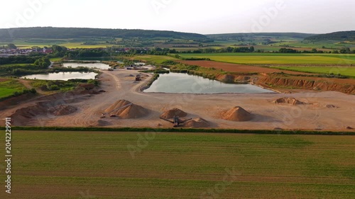 Industrial aerial view of a gravel processing plant with conveyor belts, sand piles and quarry operations producing construction materials for roads, buildings and infrastructure