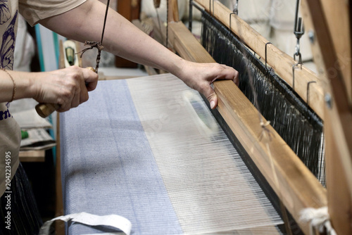 Fotografie A person weaving fabric on a traditional loom