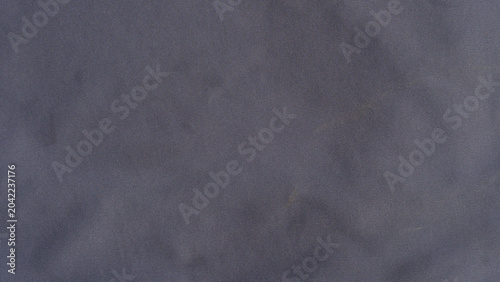 Full-frame close up of a soft dark grey microfiber cloth or suede fabric texture. Featuring subtle organic folds smooth pile directions and rich shadow depths.