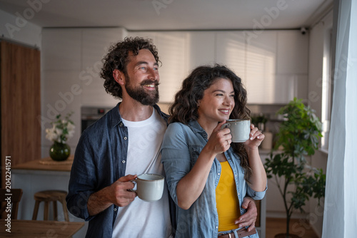 Happy couple enjoying morning coffee in kitchen at home