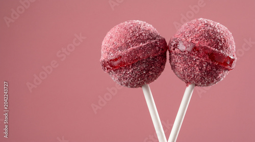 Two Red Berry Lollipops with Sugar Coating on Pink Background
