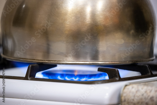 Metal cookware on a blue flame gas stove burner, close up. Cooking, kitchen appliance, heat, home cooking,