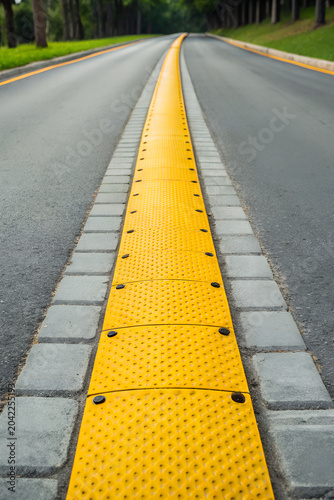 Yellow tactile guide along a road, clear visibility, designed for accessibility