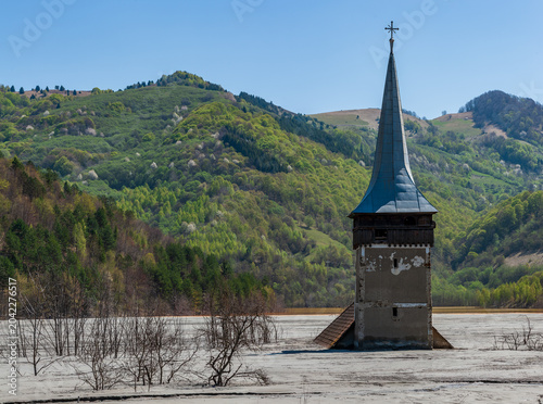 Schilderij op canvas Church tower rising from the toxic tailings lake of Geamana, flooded by mining waste from Roșia Poieni copper mine, Apuseni Mountains, Romania