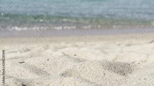 Cinematic rack focus from golden sand ripples to crystal-clear turquoise sea and blue horizon. Kal'e Moru beach, Quartu Sant'Elena, Sardinia, Italy. Cinematic mode, bright morning light, June.
