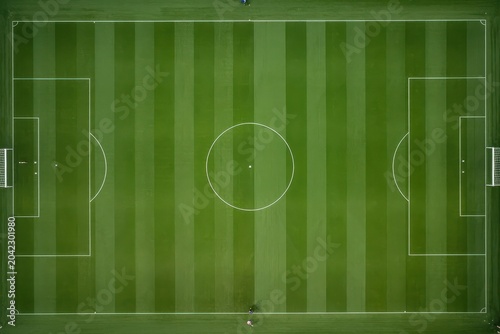 An aerial top-down view of a perfectly manicured green soccer field with white markings.