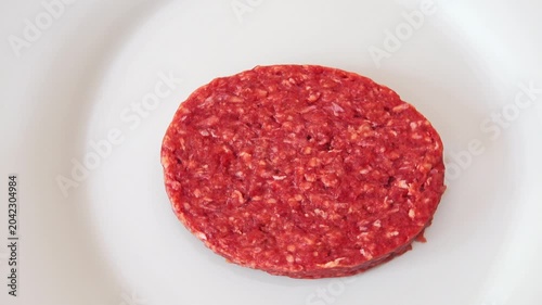 Raw hamburger patty on a plain white plate