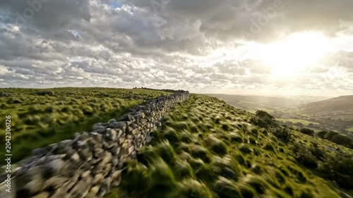 Stone wall along a windswept grassy hill at sunset