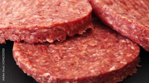raw beef patties sit on a dark surface