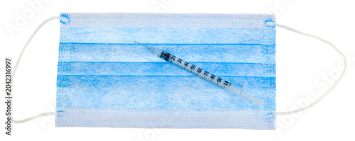 A syringe on a blue gauze mask isolated on a white background.