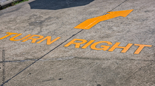 Foto High Angle View of Yellow Painted Turn Right Traffic Sign and Arrow on Concrete