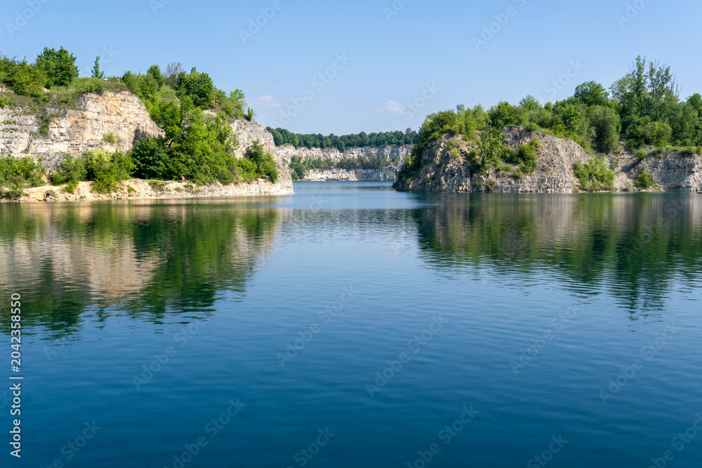 Fototapeta premium Zakrzowek quarry lake in Krakow with deep blue water and rocky cliffs, Poland