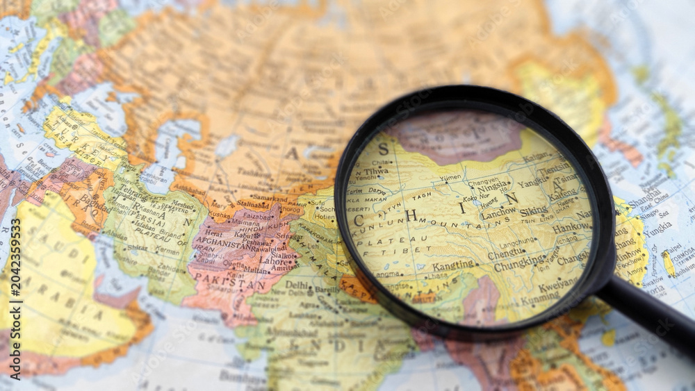 Fototapeta premium Magnifying glass highlighting China on a map, representing geographic research, regional analysis, international studies, and location identification.