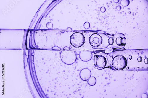Fotografie Two pipettes with cosmetic bubble liquid over petri dish