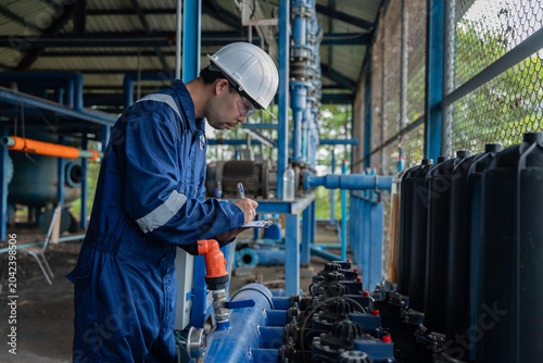 Professional engineer inspecting industrial water filtration system and membrane units in a production plant. Technician documenting performance data for water treatment process in factory station.