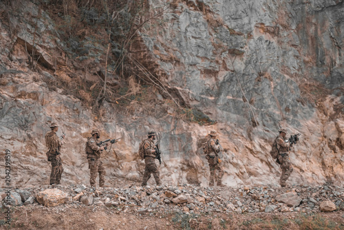 Foto Side profile view of a tactical squad patrolling along a steep mountain cliff