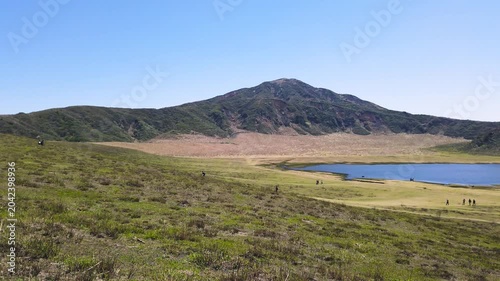 Kusasenrigahama volcanic plain inside Mount Aso caldera in Kumamoto Japan. Wide panoramic view of grasslands and fresh green fields with a pond during spring in April. 