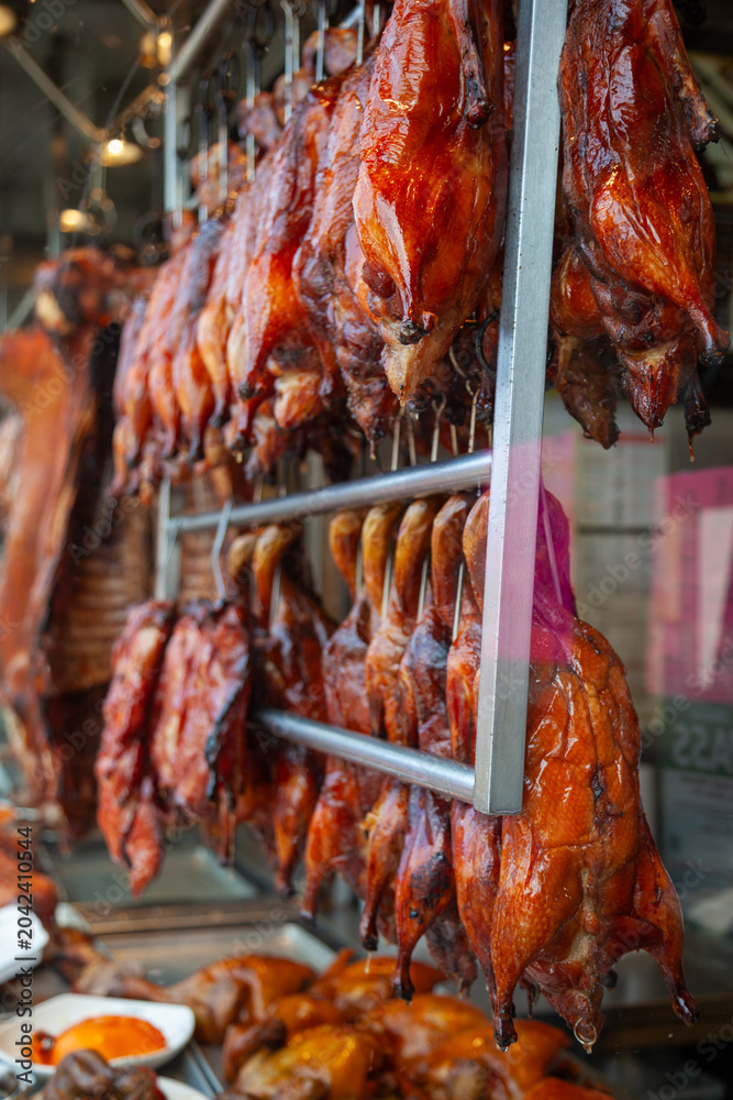Obraz premium Mahogany coloured whole roast ducks hanging on racks in a front window of a restaurant in Chinatown. Toronto, Ontario, Canada.