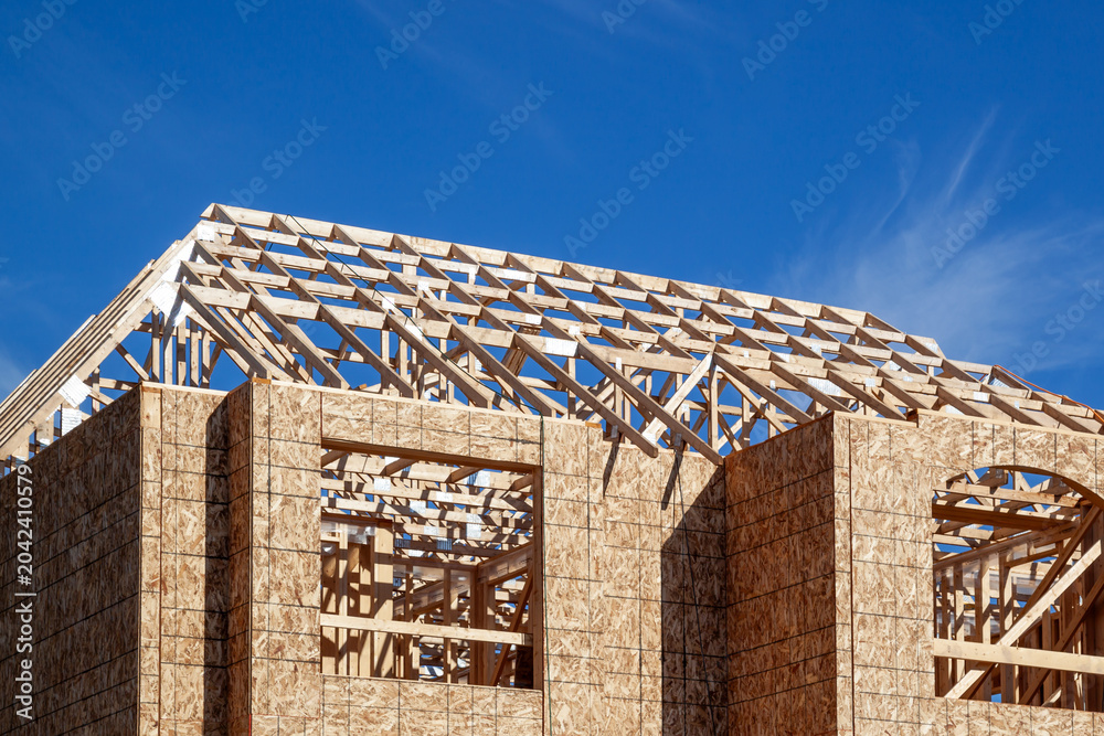 Naklejka premium The new house wood framing under construction against the blue sky. Toronto, Ontario, Canada.