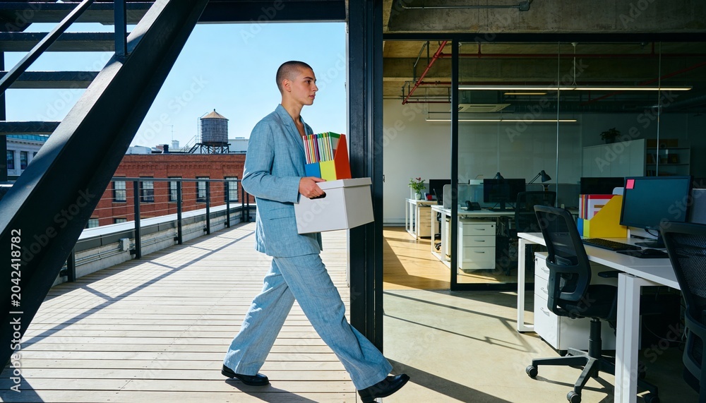 Fototapeta premium Professional person leaving office with a box of belongings. Resignation and career change concept. Employee walking on a rooftop terrace with city view