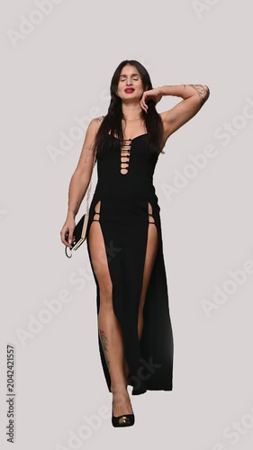 A Caucasian woman dressed in evening wear walks against a white background. Isolate. 