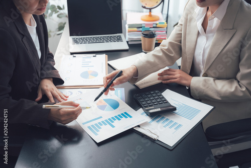 Fényképezés Business Meeting Analysis: Two businesswomen intently analyze financial charts and data on their desk, fostering collaboration and informed decision-making