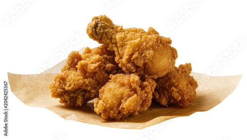 Crispy golden fried chicken pieces on brown parchment paper, isolated on transparent background