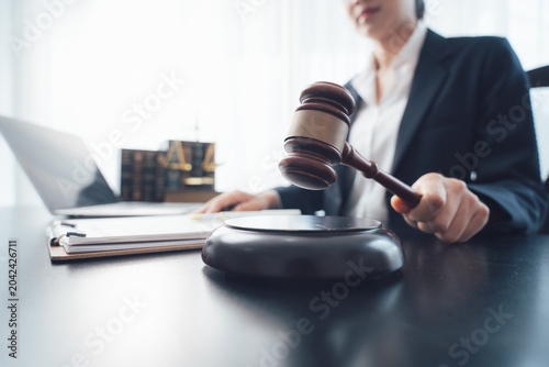 Lawyer in Action: A focused lawyer in a suit presides over legal proceedings, gavel in hand, seated at a desk with a laptop and law books, symbolizing justice and legal authority.