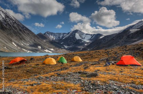 Tourist tents are set up against the backdrop of a mountain range.