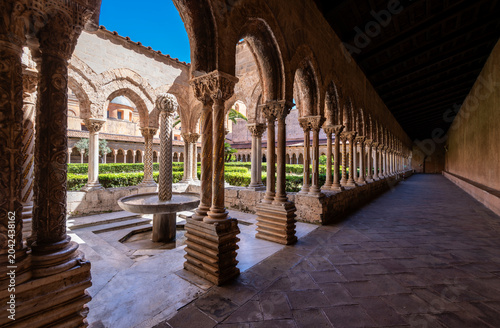 Historic fountain and decorated columns in the medieval cloister of Monreale Cathedral, Sicily, Italy