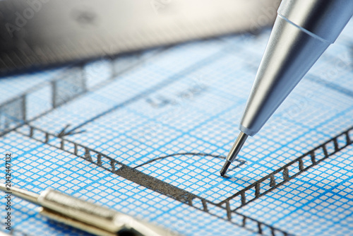 mechanical pencil makes a drawing on graph paper with ruler, dividers and tape measure. Construction and architectural industry.