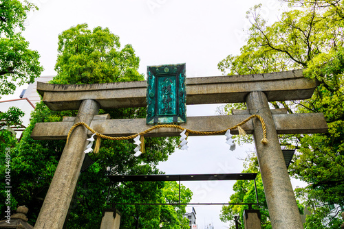 Traditional stone torii gate entrance to Yasaka Namba Shrine in Osaka, Japan. Passing through the gate marks the transition from the everyday, mundane world to a sacred space in Japan.