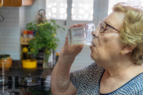 Senior woman drinking milk at home.