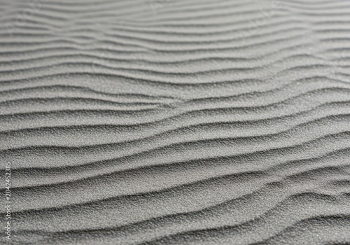 Ultra close-up of fine gray sand raked into gentle, calming waves and subtle ridges, creating a peaceful, soothing background texture, organic, soothing, texture