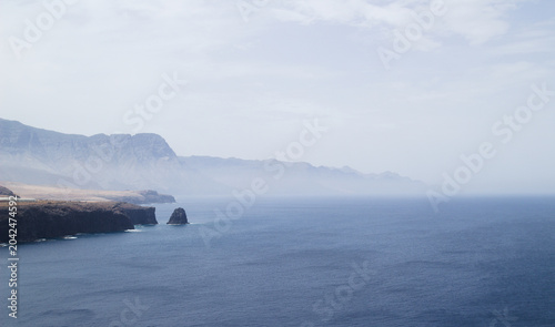 Distant View of Risco Faneque Cliff and the Cola de Dragon Mountain Formations with the Roque Partido Sea Stack on the Coastline of Gran Canaria
