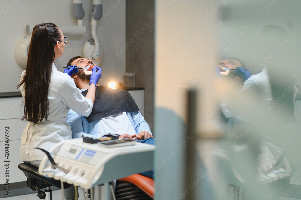 Naklejka premium Dentist examining patient's teeth in clinic