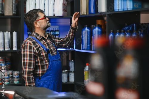 фотографія Salesman picking motor oil bottle in auto parts store