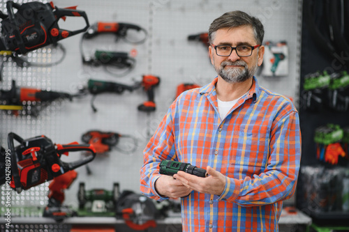 Bild auf Leinwand Salesman showing drill in hardware store with power tools
