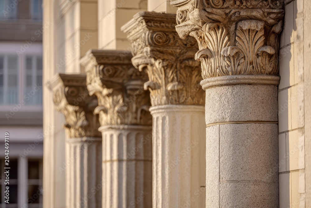 Fototapeta premium Morning light over four stone columns on a civic building facade, architectural texture and detail