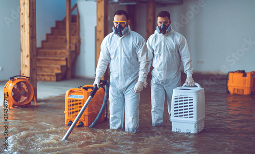 Flood restoration crew cleaning flooded home interior