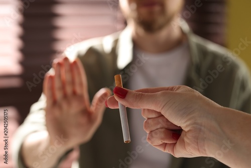 Foto Man refusing cigarette from woman indoors, selective focus