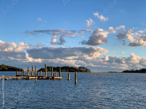 A quiet dock extends into calm coastal waters beneath dramatic evening clouds in Swansboro, North Carolina, capturing the peaceful atmosphere of the coast.