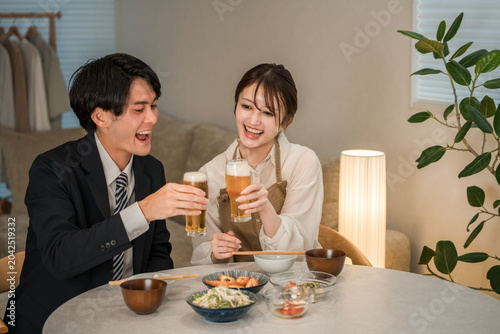 A young Asian couple enjoying a meal and drinks at their dining table in their home.