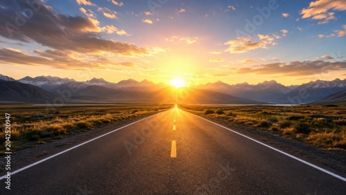 Empty road leading toward sunrise over mountain landscape