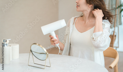 Konstfotografi A woman blow-drying her hair with a hairdryer (hair care)