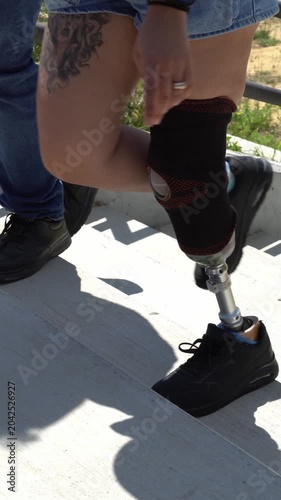 Courageous young woman with a leg prosthesis walking down stairs with a companion. Inspiring video about overcoming physical challenges
