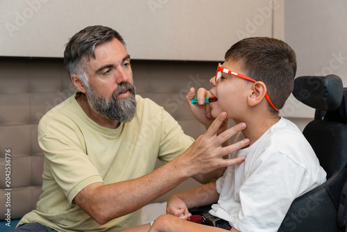 Father giving medicine to boy with cerebral palsy