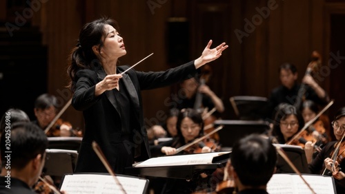 Orchestra conductor directing musicians in concert hall
