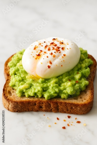 Avocado toast topped with a poached egg and red chili flakes on
